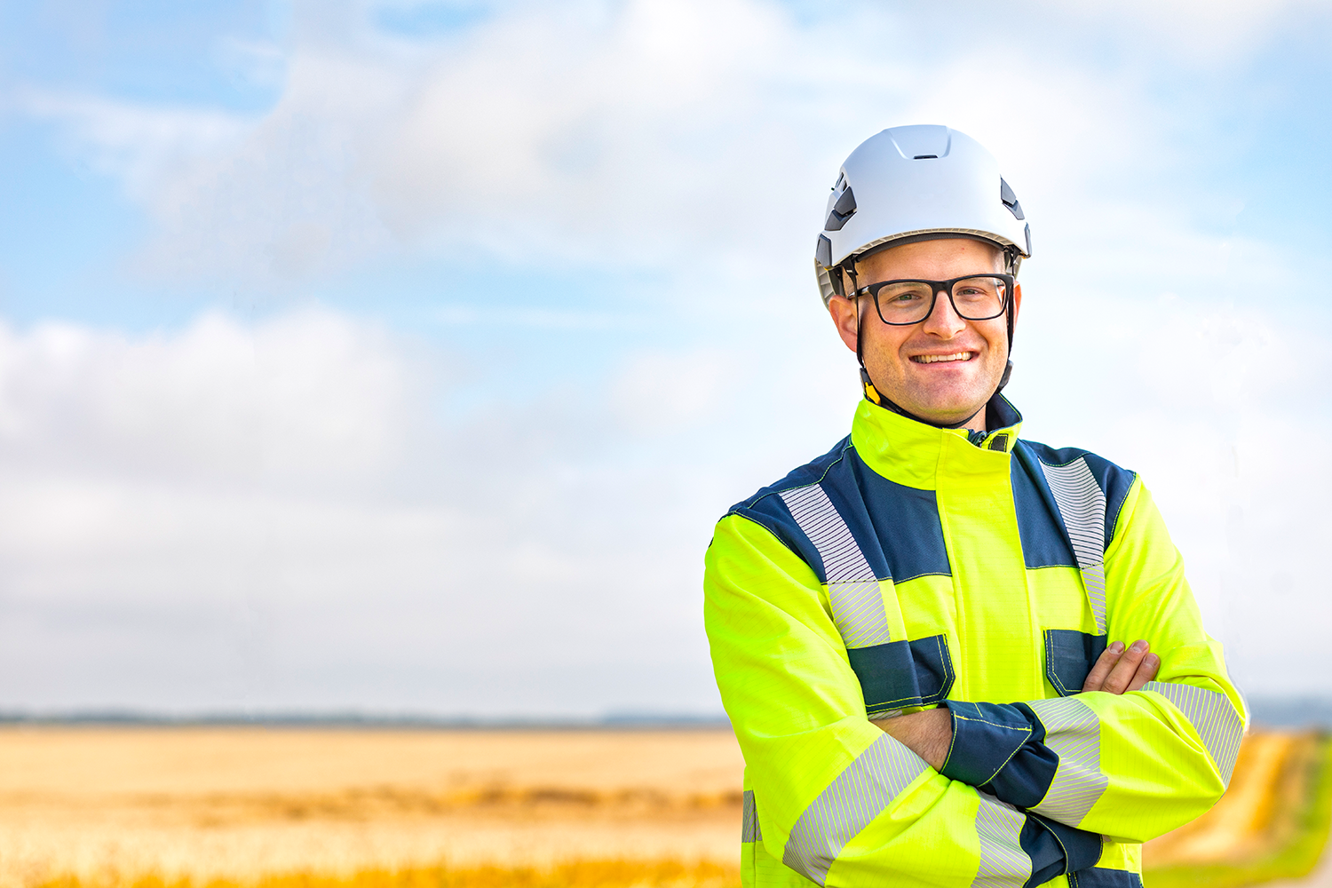 Monteur der Netze ODR im Vordergrund in Arbeitskleidung, im Hintergrund ein Getreideacker