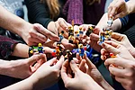 Lego-Männchen werden von verschiedenen Personen in der Hand gehalten