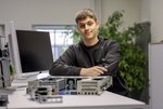 Fachinformatiker stehend am Schreibtisch mit auseinandergebautem Server